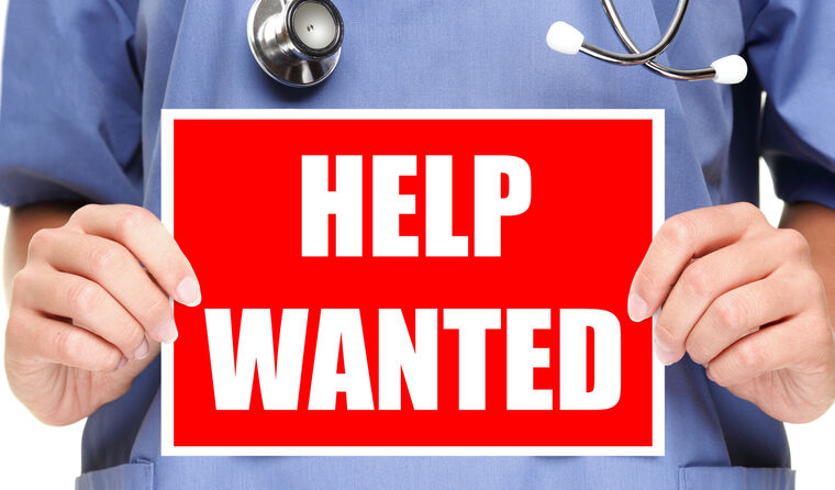 Doctor holding a 'help wanted' sign