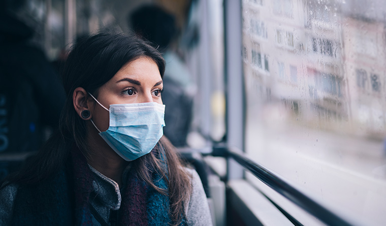 Young woman sitting on a bus wearing a face mask.